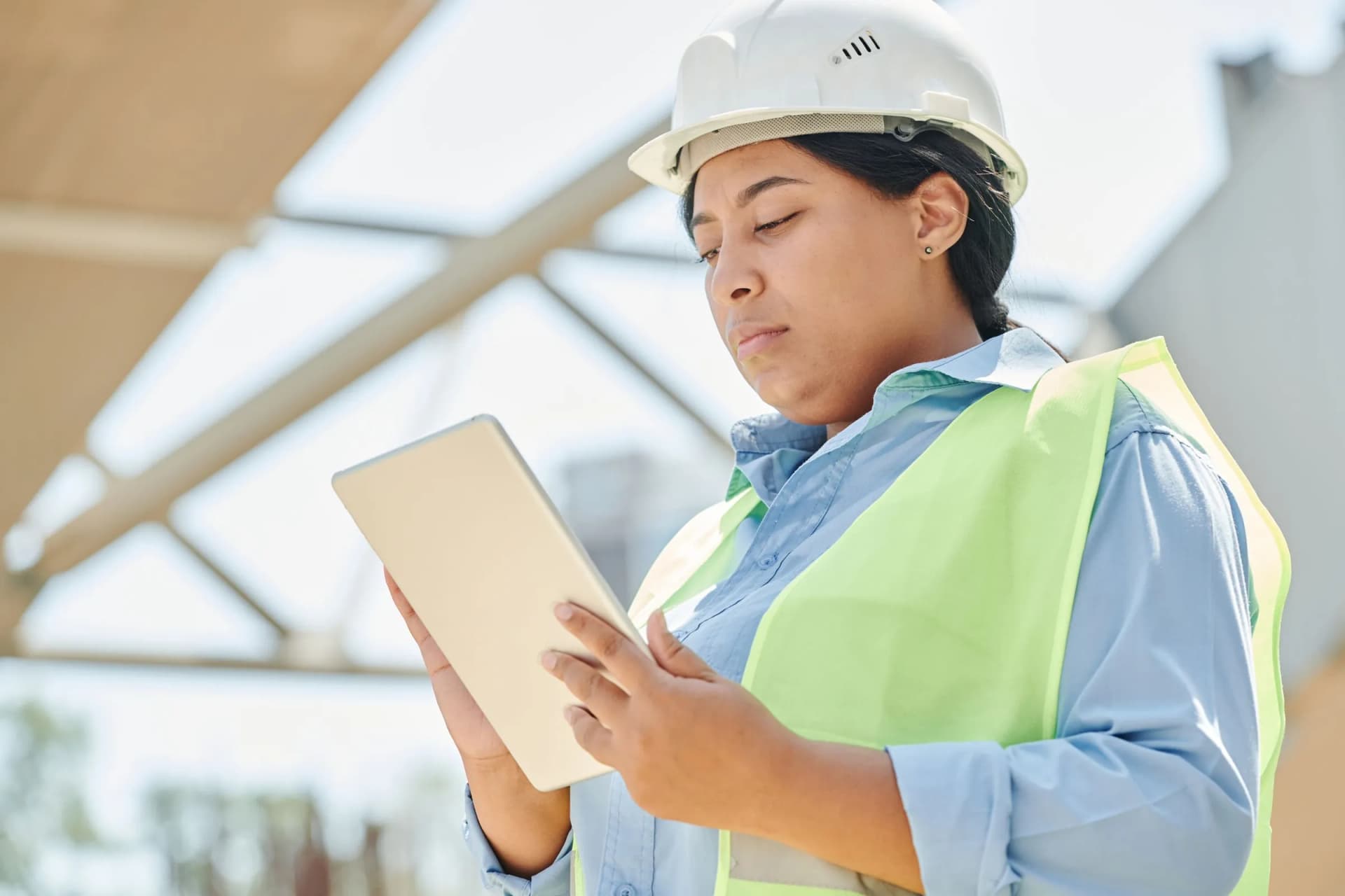 Técnica con casco y chaleco consultando una tableta en una obra