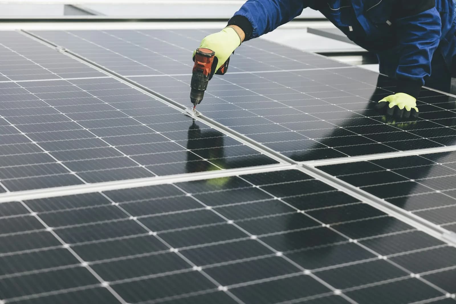 Operario fija con un atornillador un panel solar durante su montaje