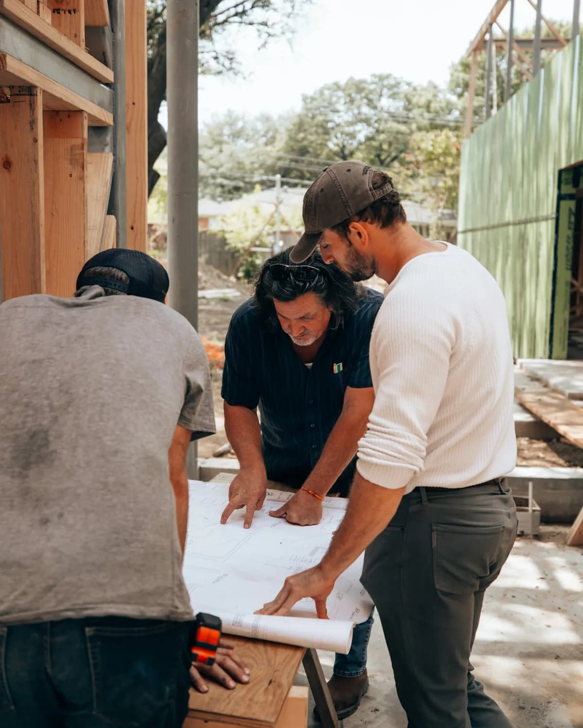 Tres personas revisan un plano sobre una mesa en una obra