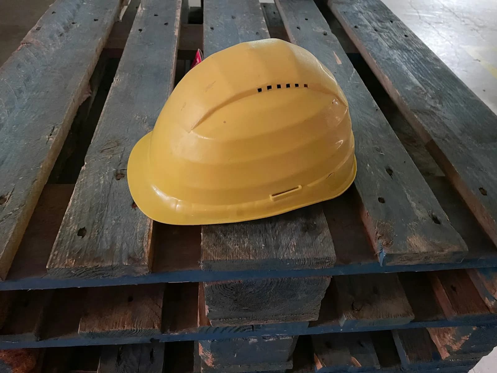 Casco de obra amarillo sobre un palet de madera